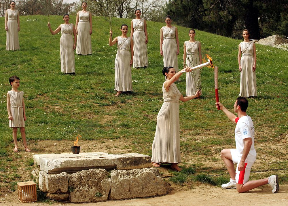 Actress Maria Nafpliotou (C) in the role of the High Priestess lights the torch of the Olympic Flame of the first torchbearer Alexandros Nikolaidis , Olympic winner of Tae Kwo Do , during the rehearsal of Lightning Ceremony of the Olympic Flame for Beijing summer Olympics, in front of Hera Temple in Ancient Olympia,  23 March 2008. EPA/ORESTIS PANAGIOTOU